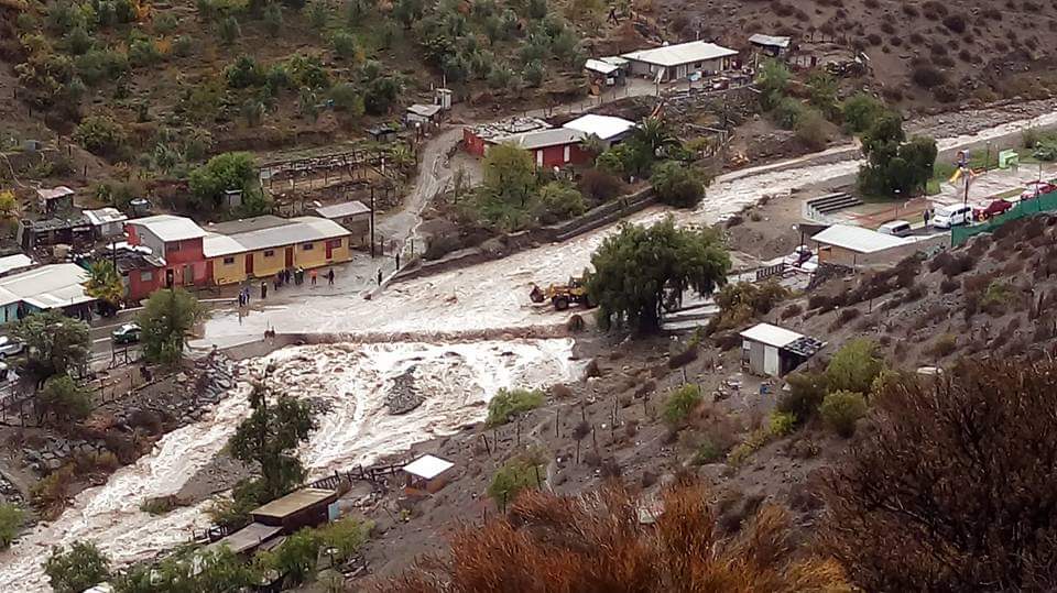Registro de un cauce con agua junto a viviendas y caminos de la comunidad